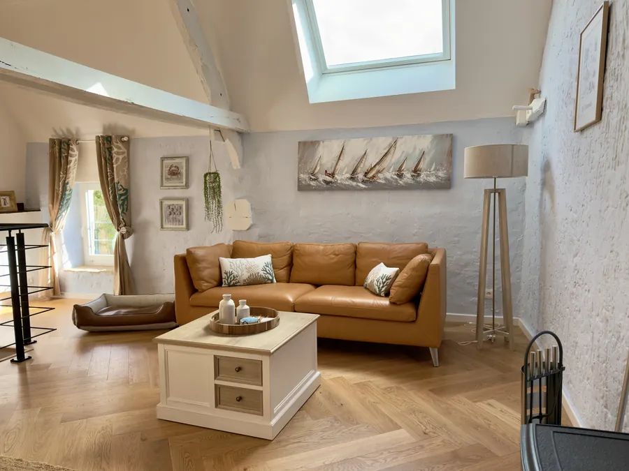 Wohnzimmer mit Ledersofa, Fischgrätparkett und Hundebett