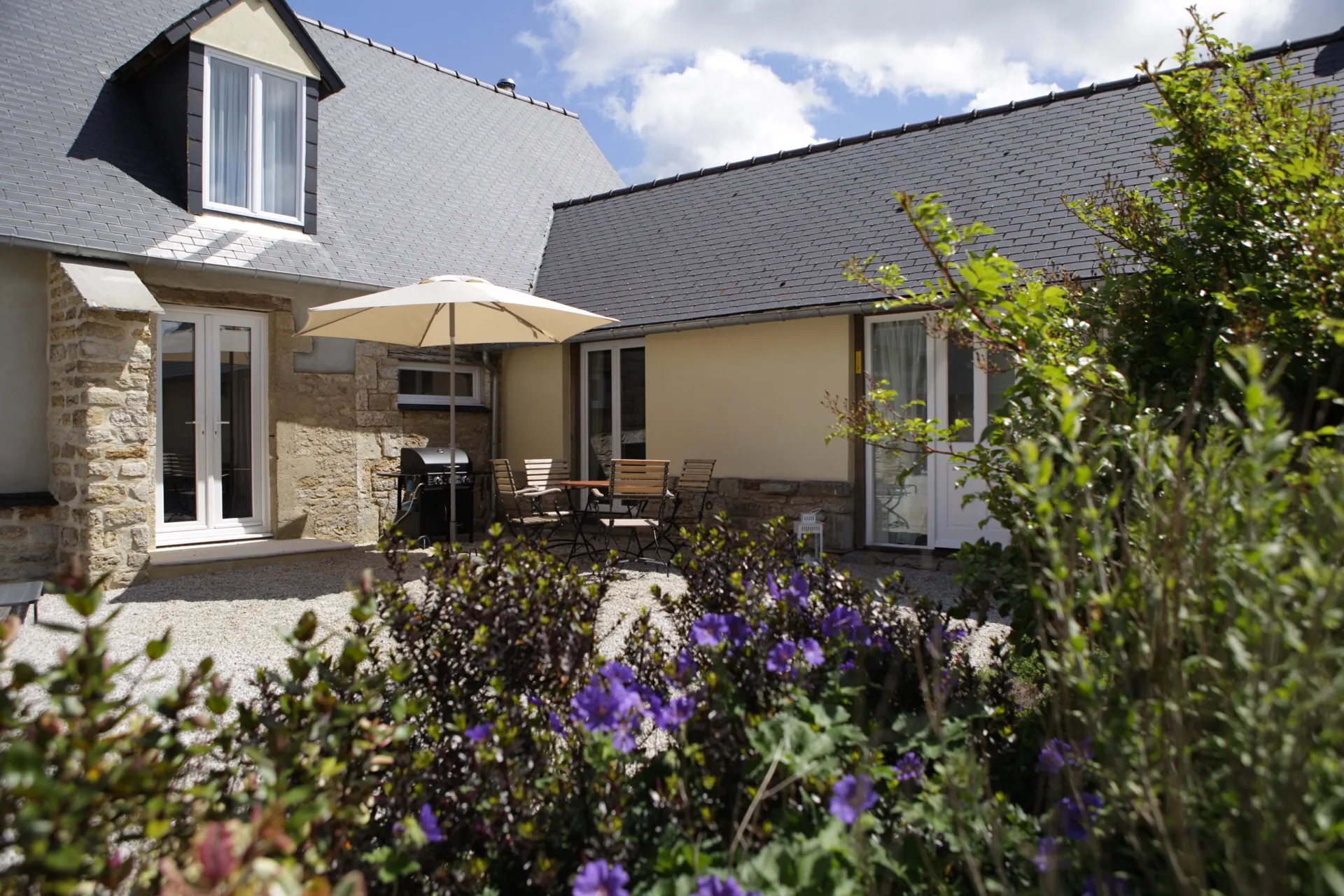 Sitzgruppe mit Sonnenschirm im ruhigen Innenhof von Maison les Grues