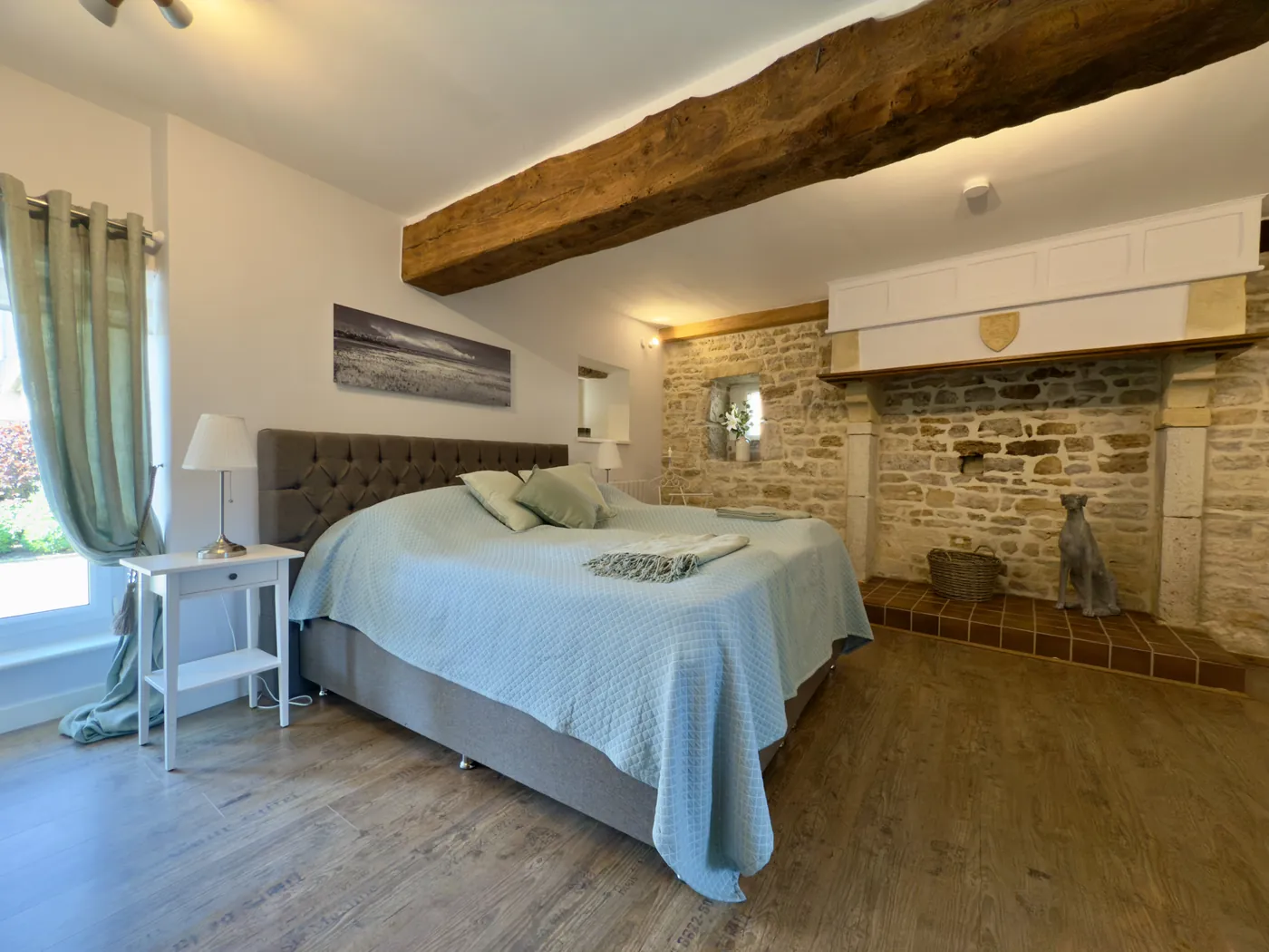 Schlafzimmer im Erdgeschoss mit Boxspringbett und Natursteinwand