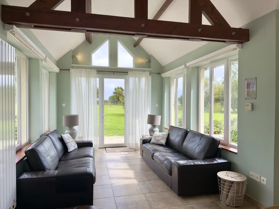 Wintergarten mit zwei Ledersofas und Hundebett, Blick in Garten und Marschland