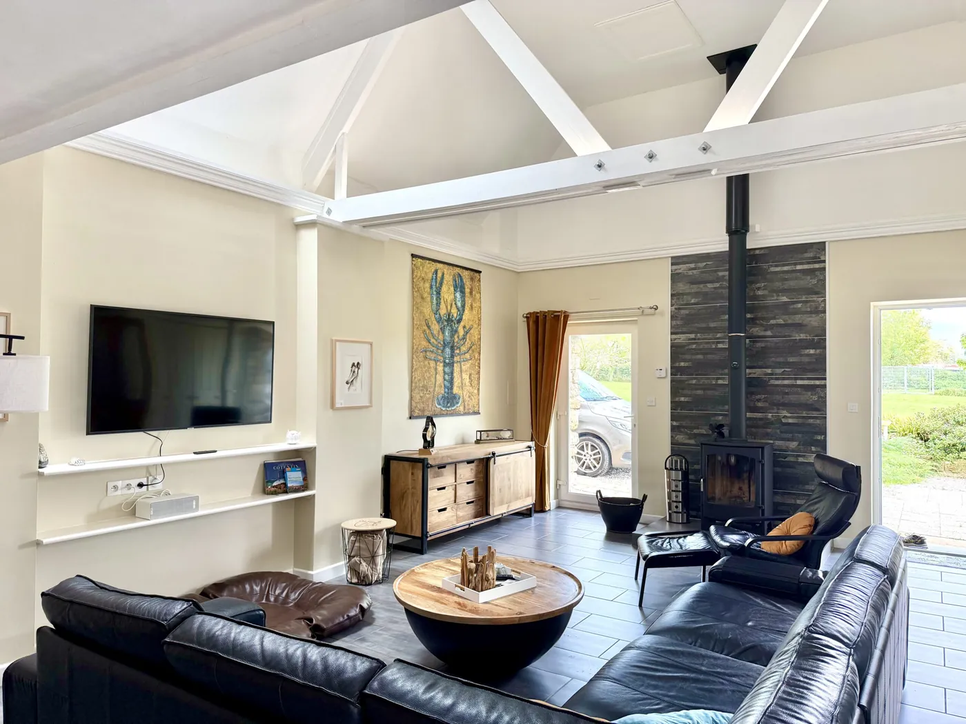Wohnzimmer von Maison les Grues mit Ledersofa, Kaminofen und Smart-TV