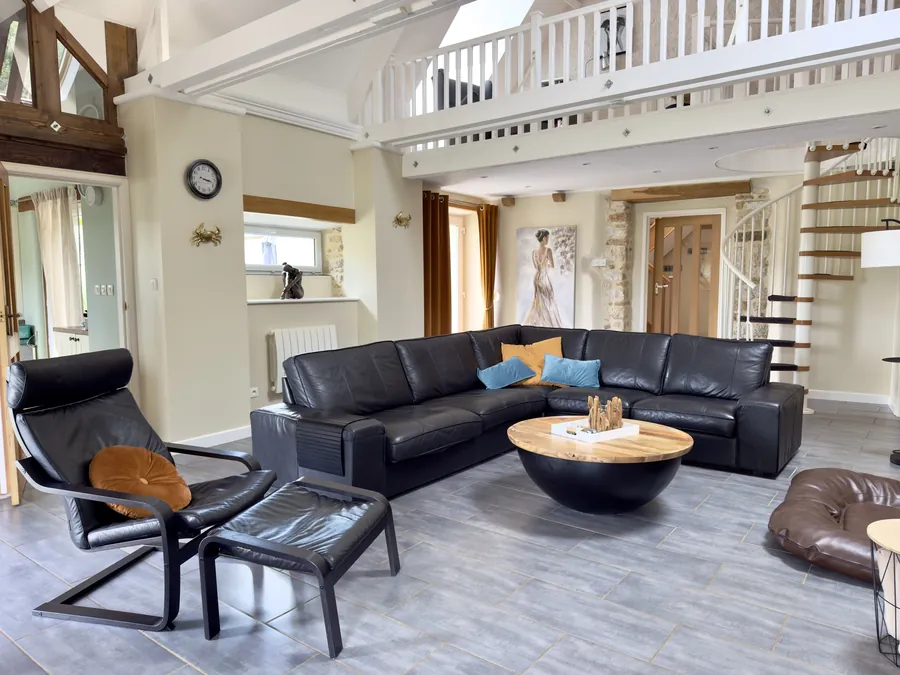 Wohnzimmer mit Ledersofa, Sessel und Aufgang zur Galerie